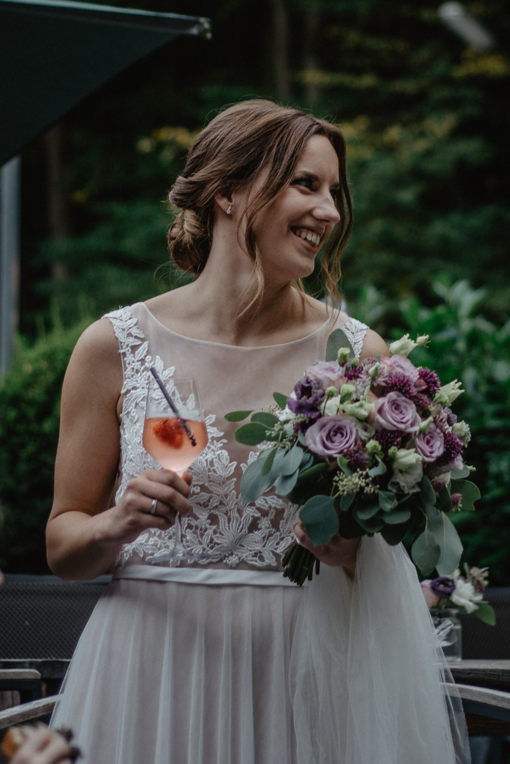 Braut hält ihren Strauß aus Rosen und Eukalyptus während des Empfangs.