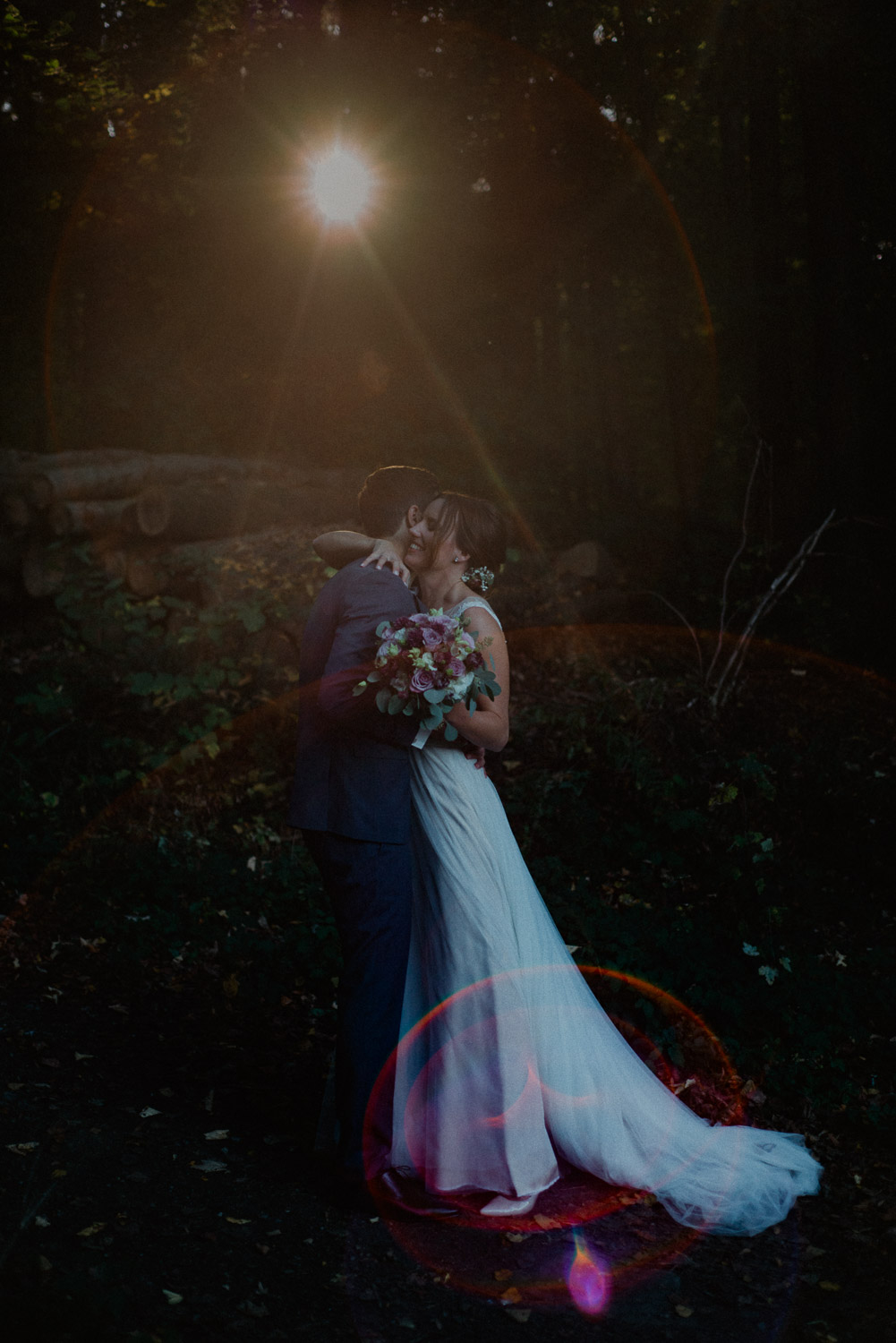 Brautpaar umarmt sich im Wald bei Sonnenuntergang während der Herbsthochzeit.