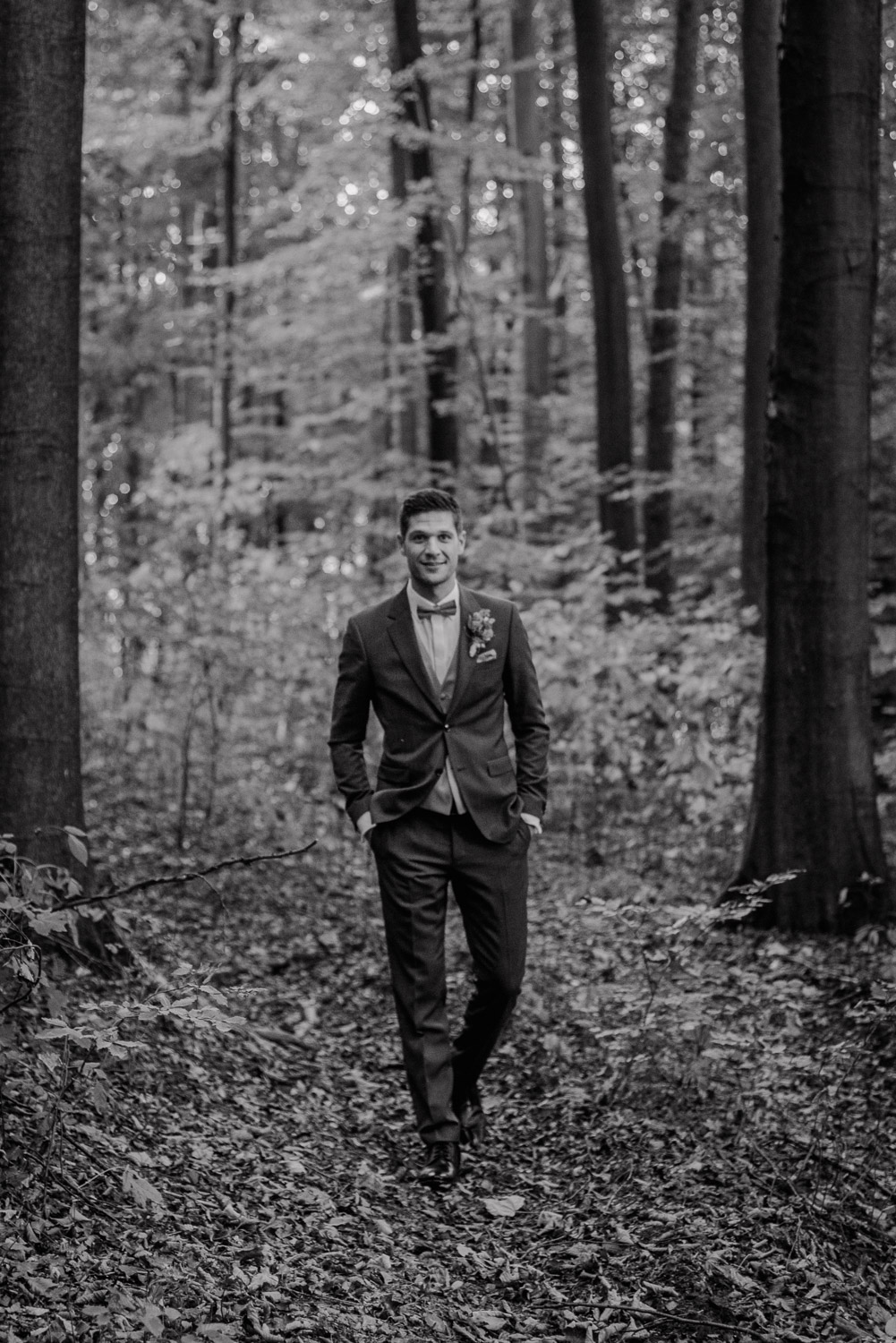 Bräutigam geht durch den Wald, Schwarz-Weiß Aufnahme.