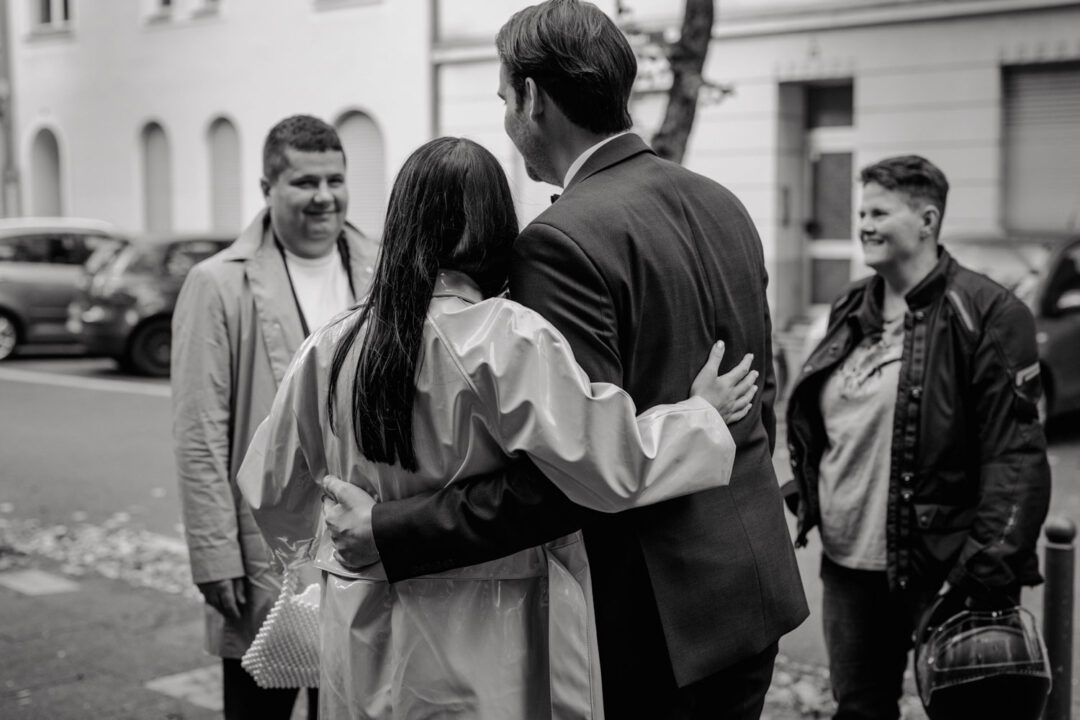 Gleichgeschlechtliches Brautpaar trifft Gäste vor der Kirche in Köln