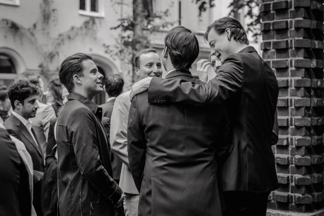 Gäste in Anzügen unterhalten sich vor der Kirche in Köln