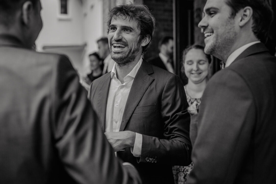 Gast gratuliert lachend beim Hochzeitsauszug