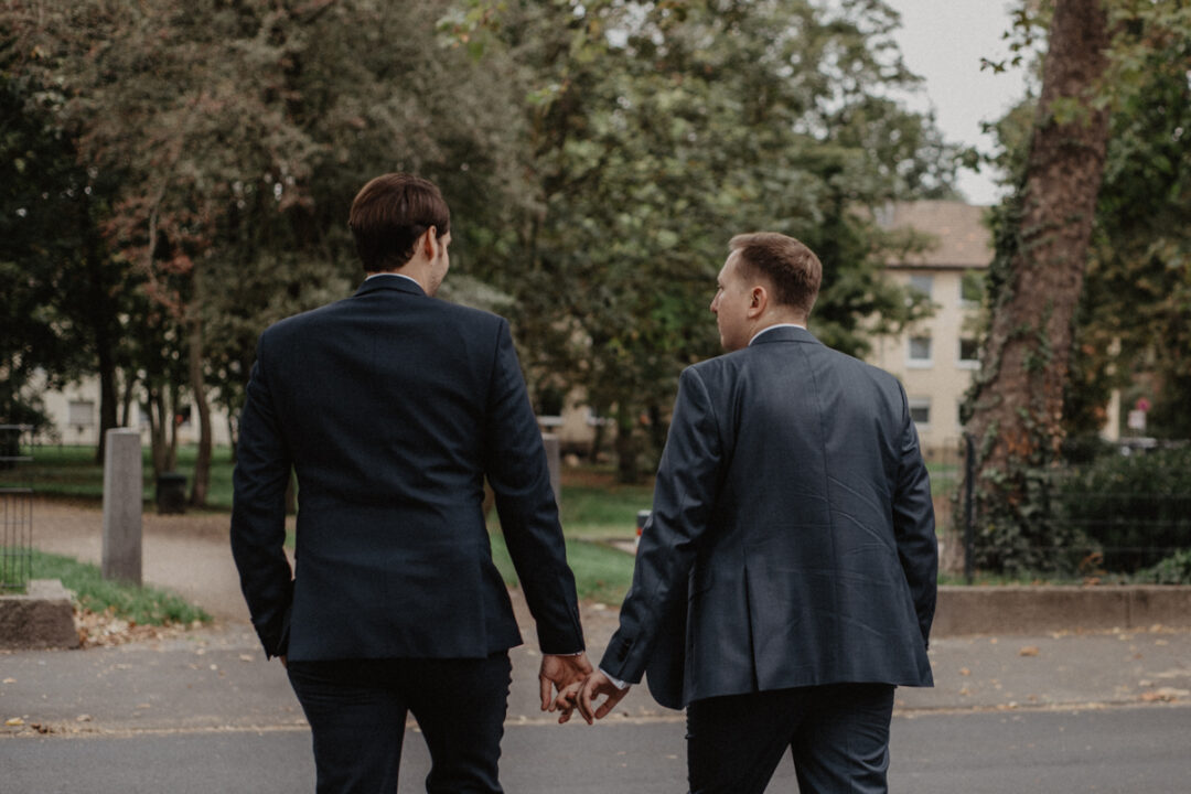 Zwei Bräutigame spazieren nach der Hochzeit durch Köln