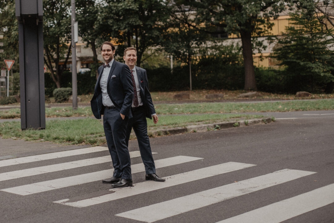 Bräutigame stehen gemeinsam auf dem Zebrastreifen
