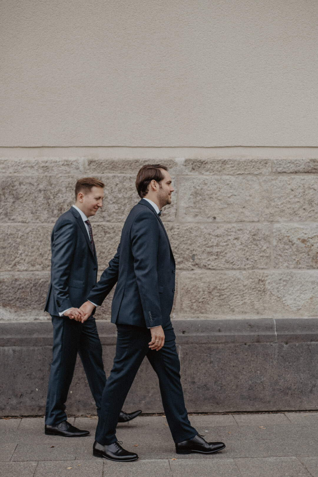 Zwei Bräutigame halten Händchen beim Spaziergang