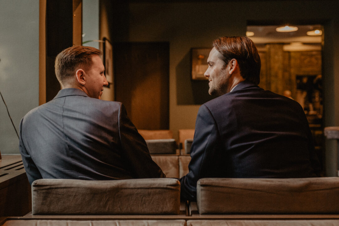 Hochzeitspaar sitzt Rücken zur Kamera vor Trauung