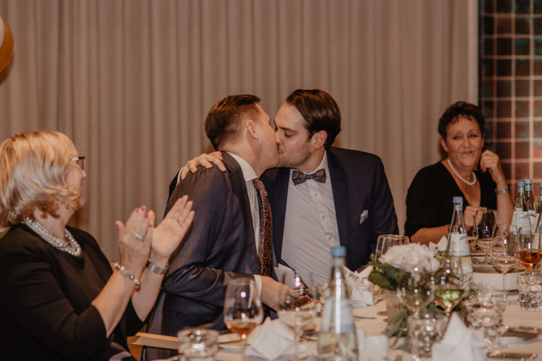 Bräutigame küssen sich bei Hochzeitsdinner in Köln