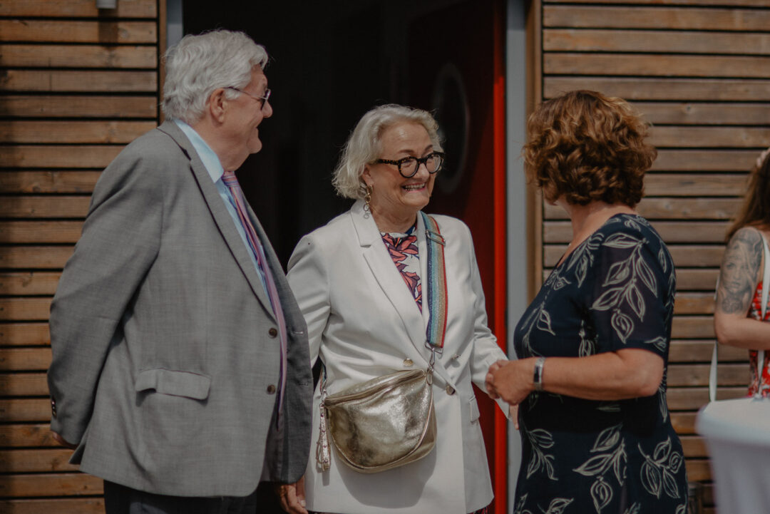 Gäste im Gespräch vor Holzwand