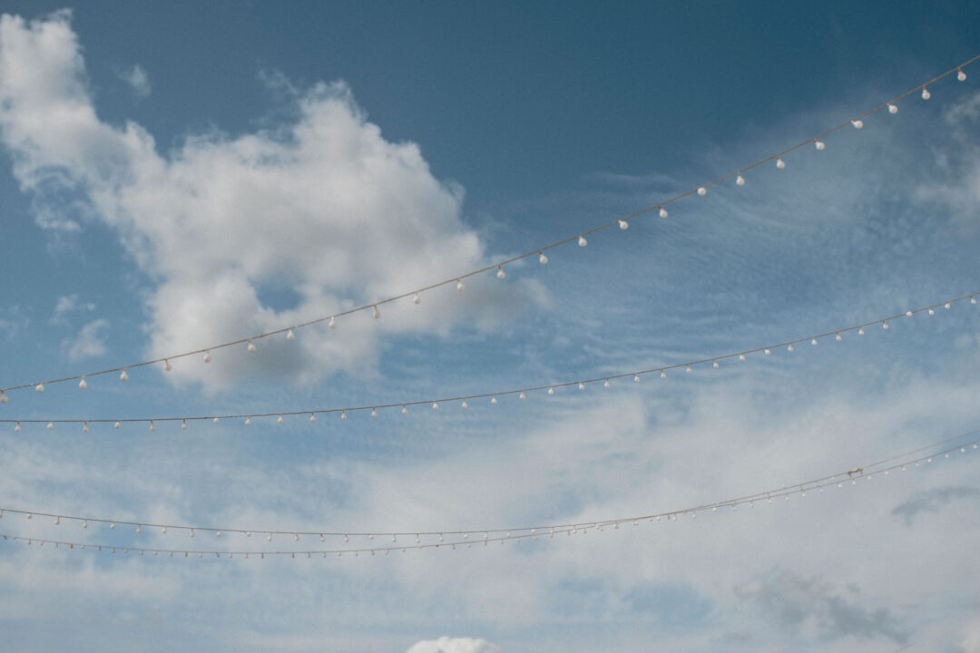Lichterketten vor blauem Himmel bei Sommerhochzeit