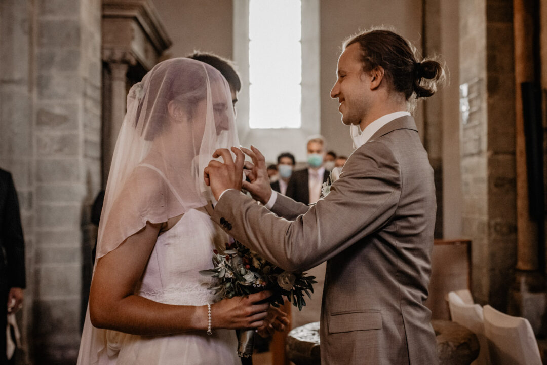 Bräutigam lüftet den Schleier der Braut in Kirche Hennen