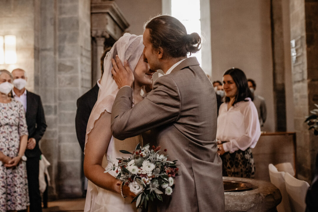 Bräutigam küsst Braut nach Schleierlüften in Kirche Hennen