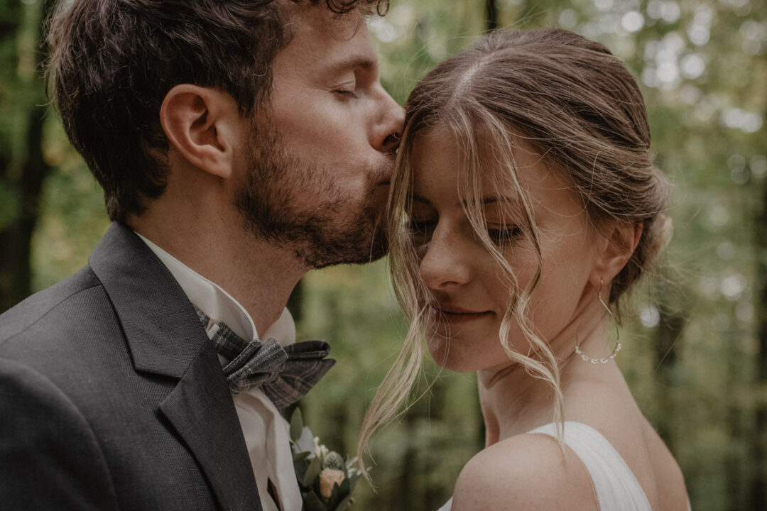 Bräutigam küsst Braut liebevoll auf die Stirn