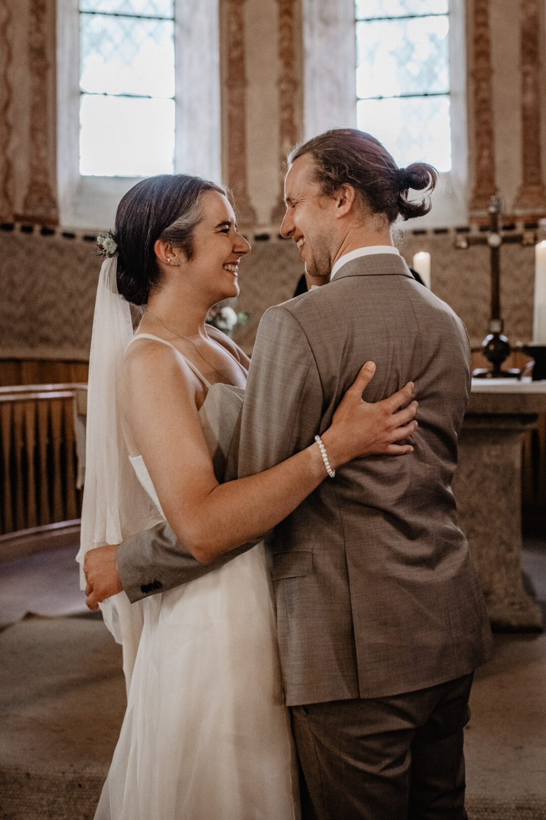 Frisch verheiratetes Brautpaar umarmt sich in Kirche