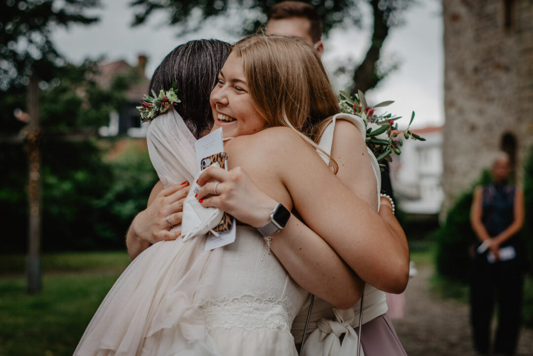 Braut umarmt Freundin nach kirchlicher Trauung