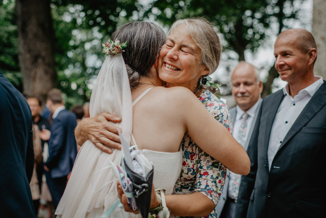 Braut wird von Mutter umarmt nach kirchlicher Trauung