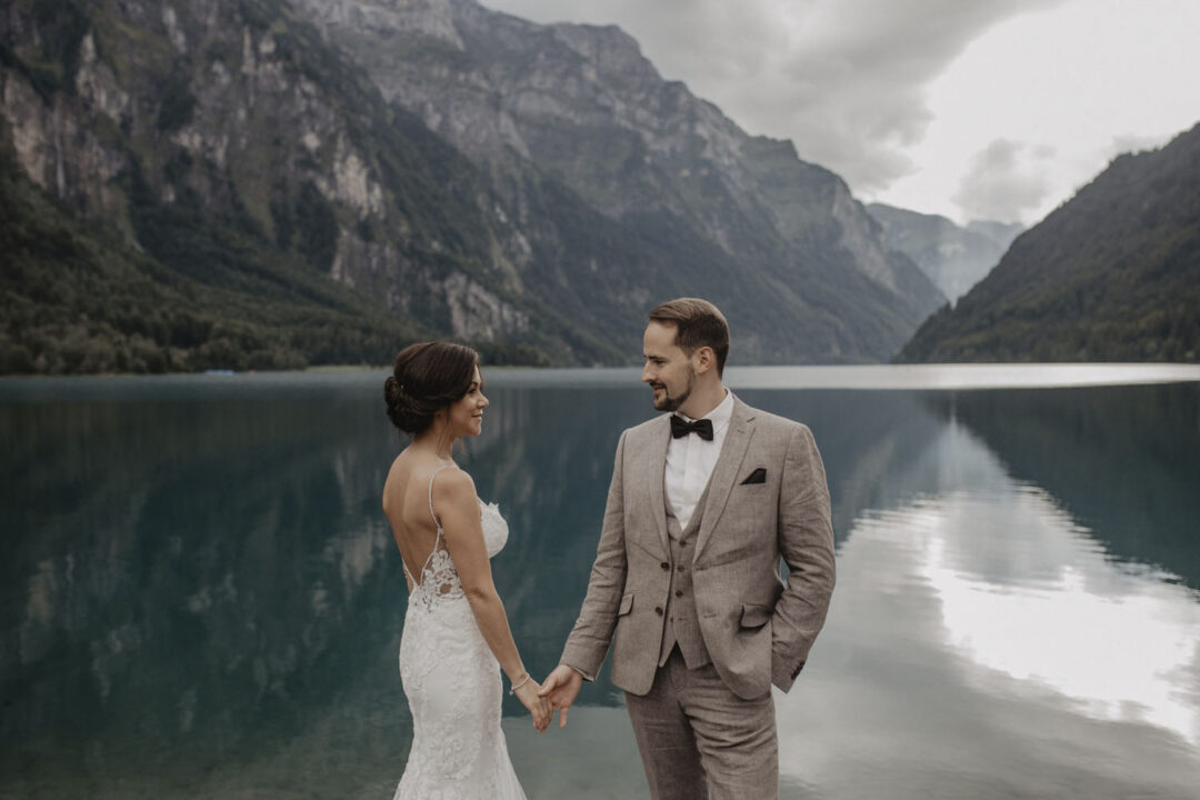 Brautpaar hält sich an der Hand vor dem See