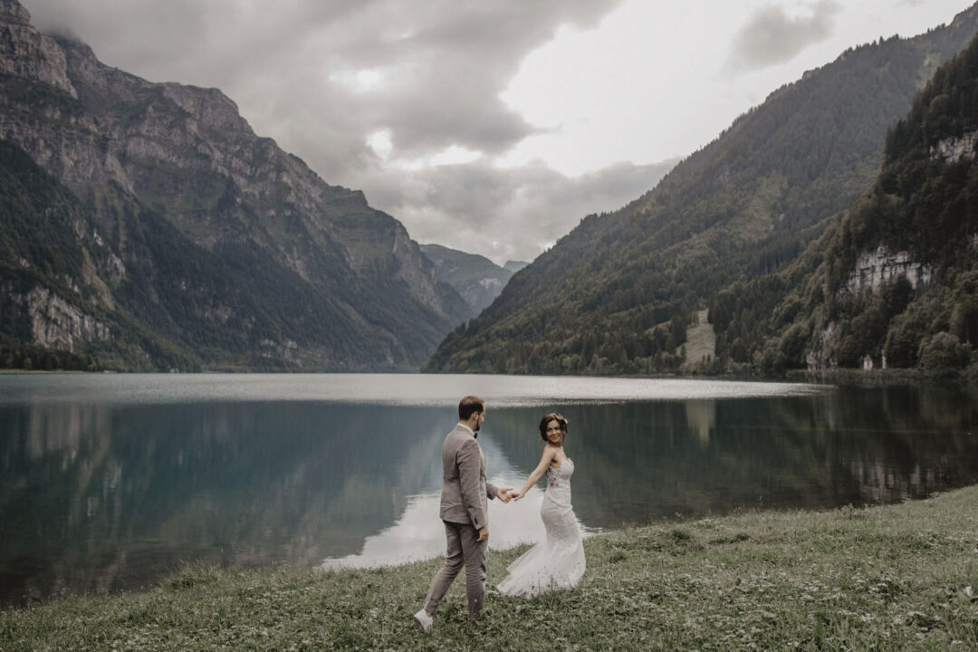 Hochzeitspaar geht am Seeufer entlang