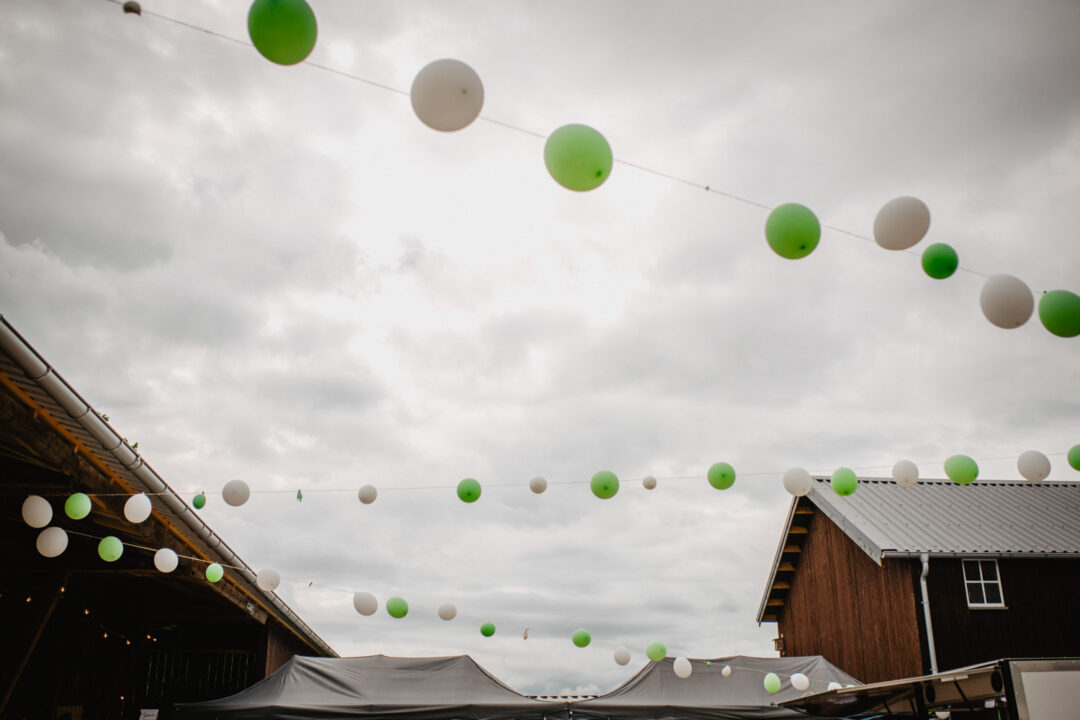 Grüne und weiße Luftballons über Hochzeitsscheune