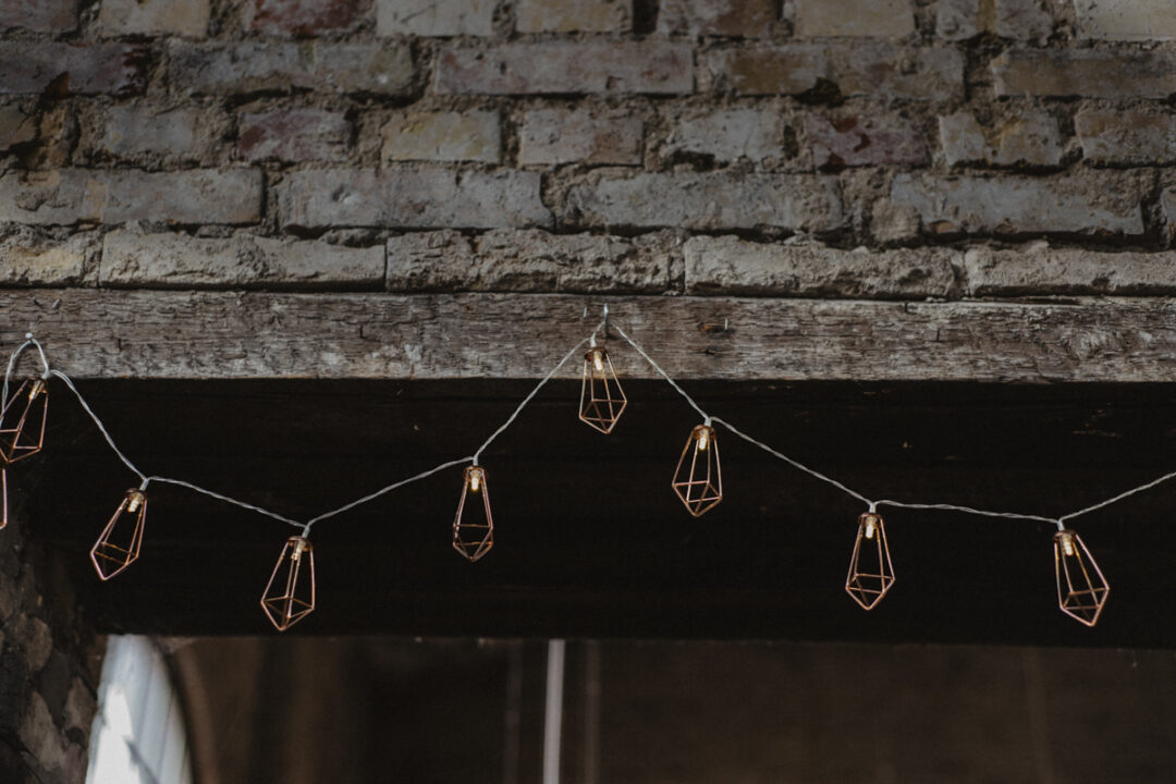 Kupferfarbene Lichterkette an Holzbalken in der Hochzeitslocation