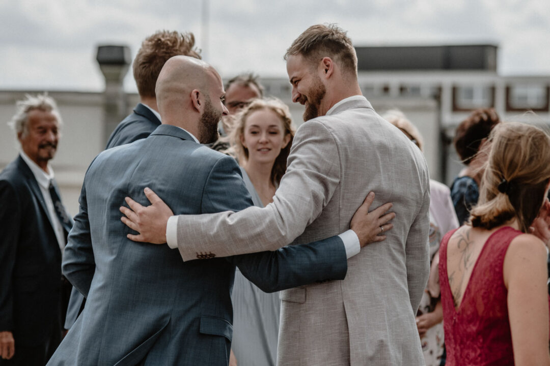 Bräutigam umarmt Gäste beim Sektempfang