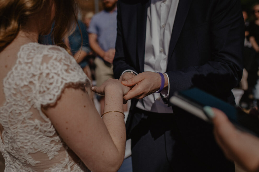 Bräutigam steckt Braut den Ring an