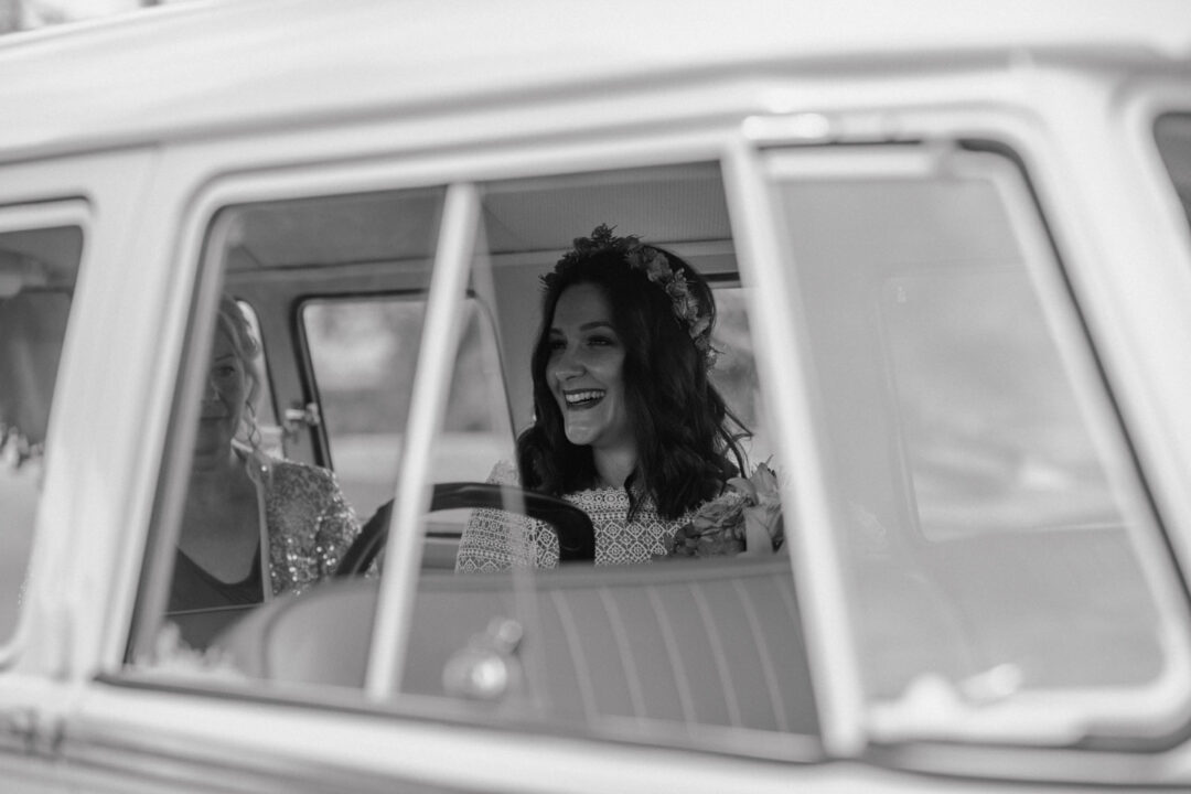 Lachende Braut im VW Bulli vor der Trauung