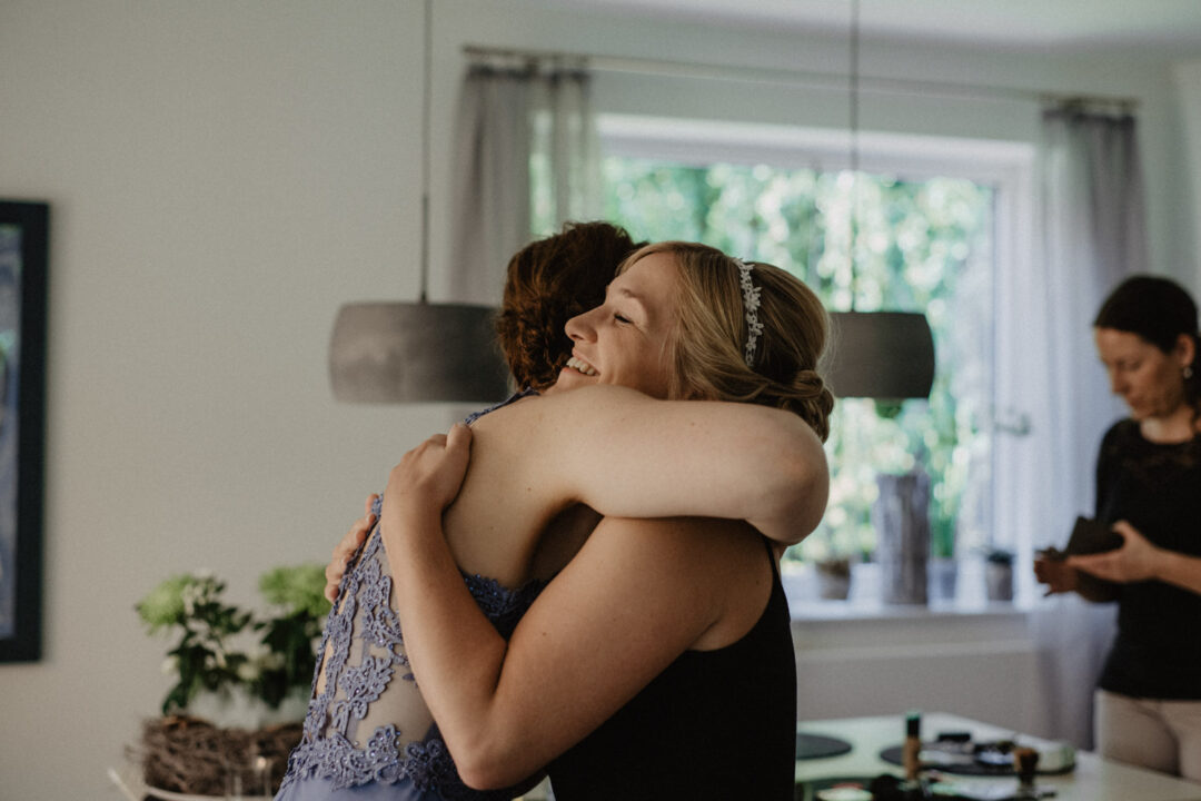 Braut umarmt eine Freundin im hellen Raum