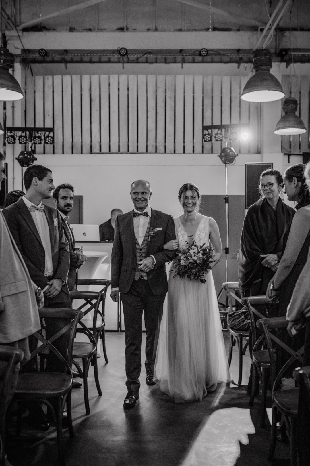 Braut wird von ihrem Vater in Schwarzweiß zur Trauung geführt