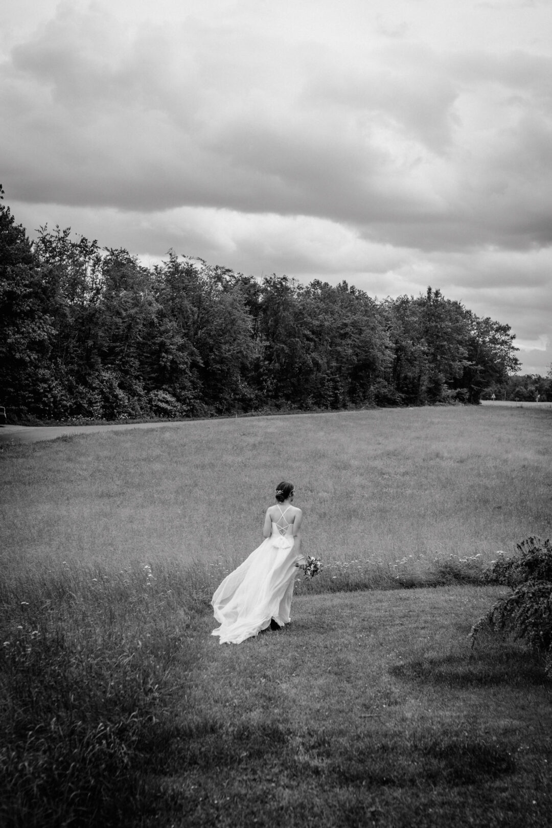 Braut mit Blumenstrauß in weiter Wiese