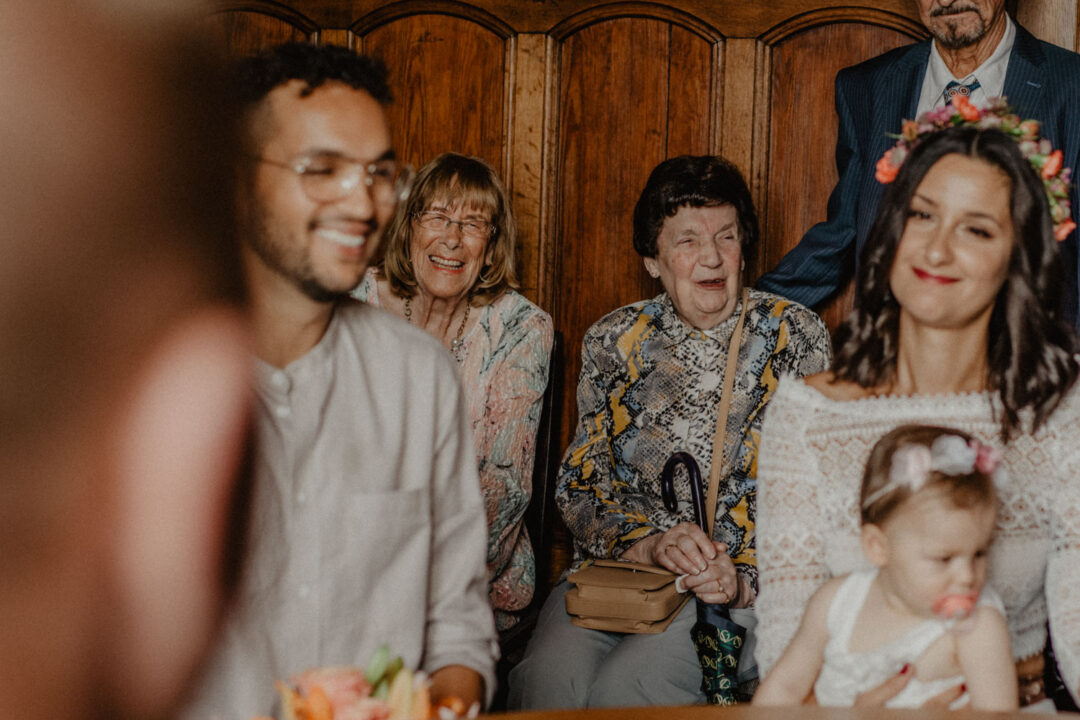 Hochzeitsgäste lächeln und freuen sich im Trauzimmer