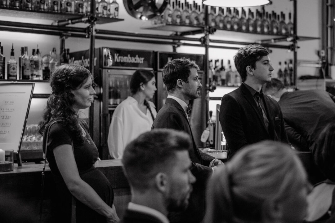 Hochzeitsgäste unterhalten sich an der Bar in Schwarzweiß