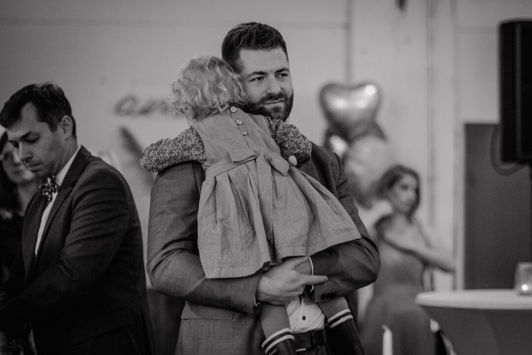 Vater trägt Kind auf Schultern während der Hochzeitsfeier