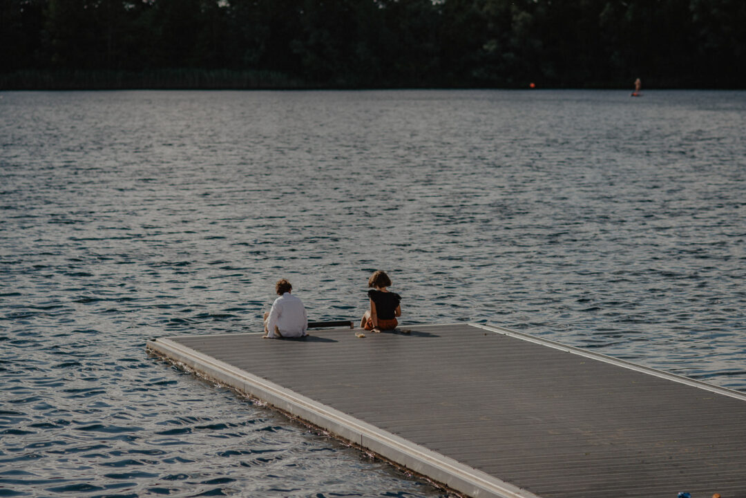 Zwei Kinder sitzen auf dem Steg