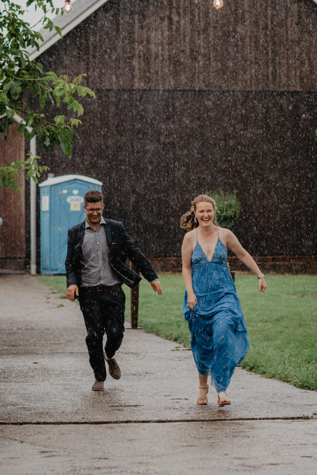 Paar rennt lachend im Regen zur Feier