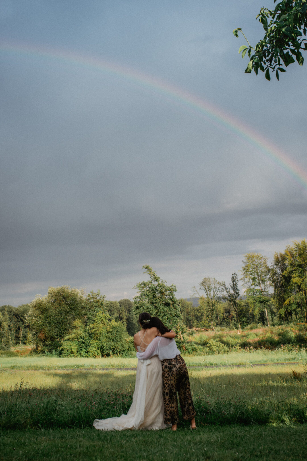 Braut schaut mit Freundin auf Regenbogen