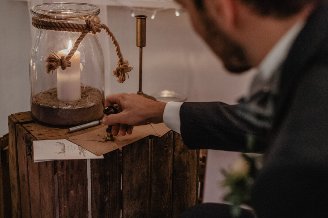 Bräutigam versiegelt symbolischen Brief mit Siegelwachs