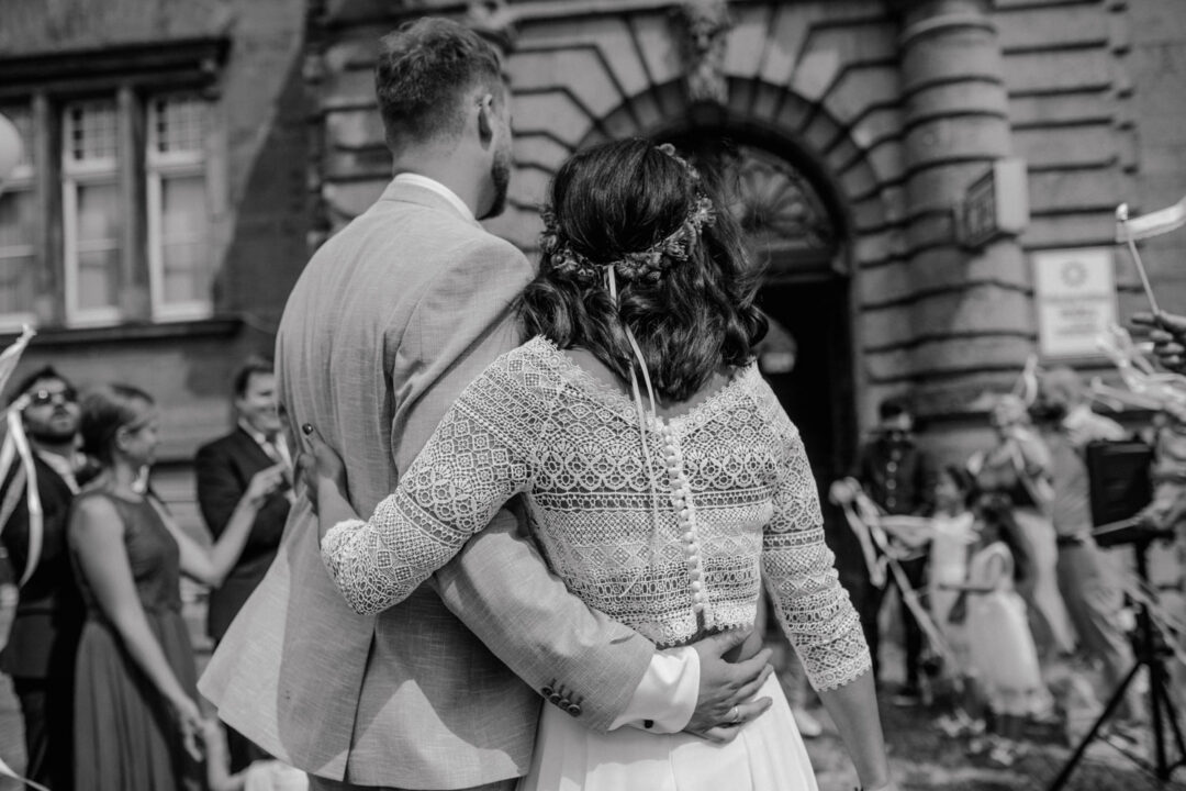 Brautpaar blickt auf das Standesamt zurück