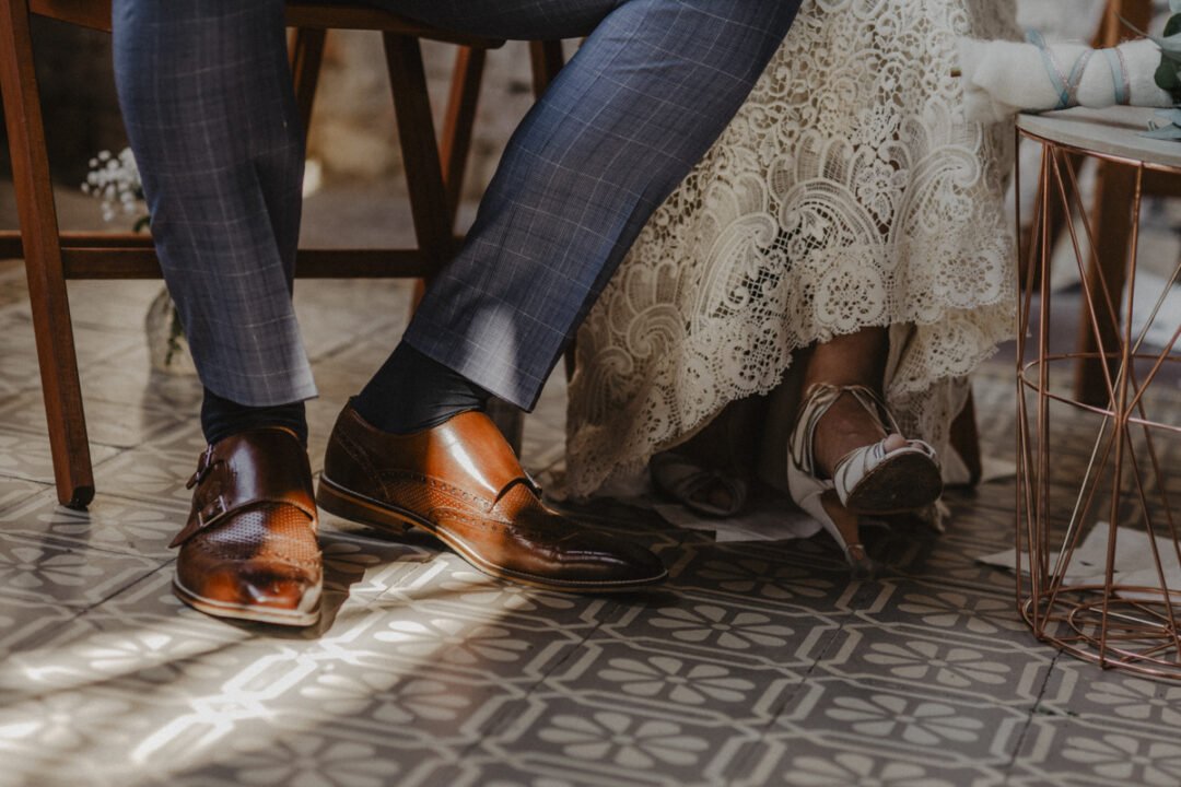 Detailaufnahme der Schuhe von Braut und Bräutigam auf gemustertem Boden