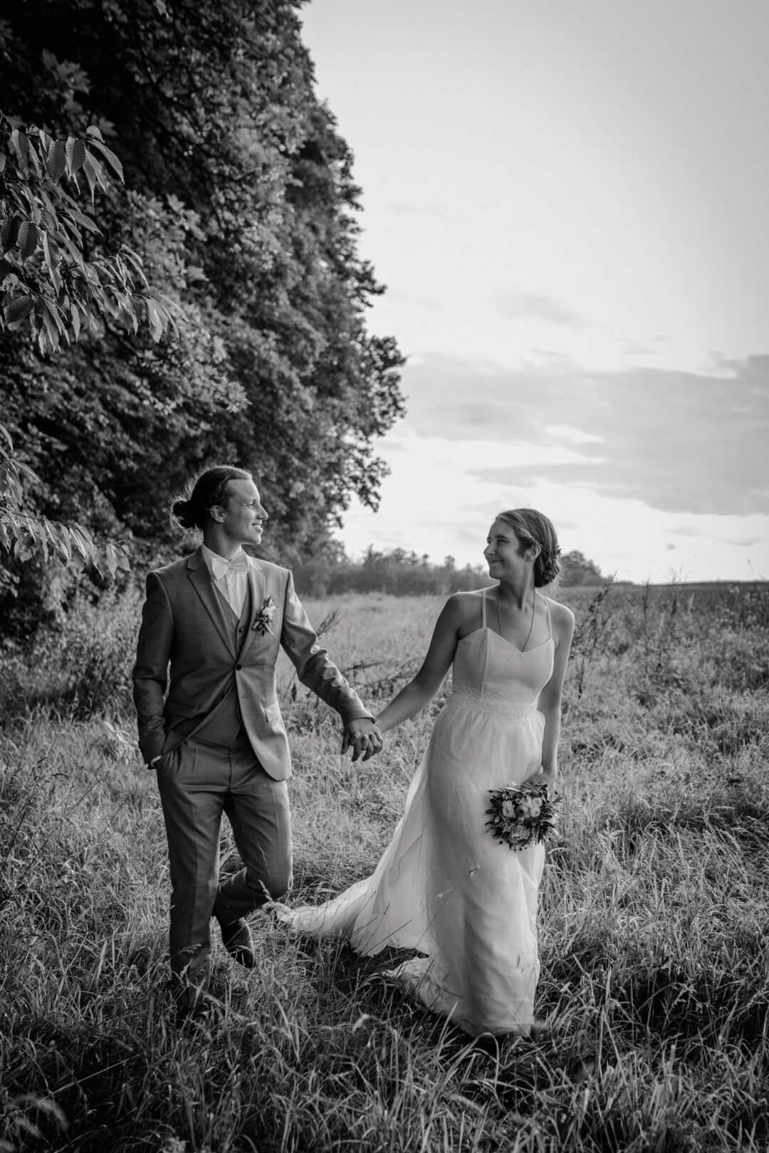 Paar geht Hand in Hand durch Sommerwiese