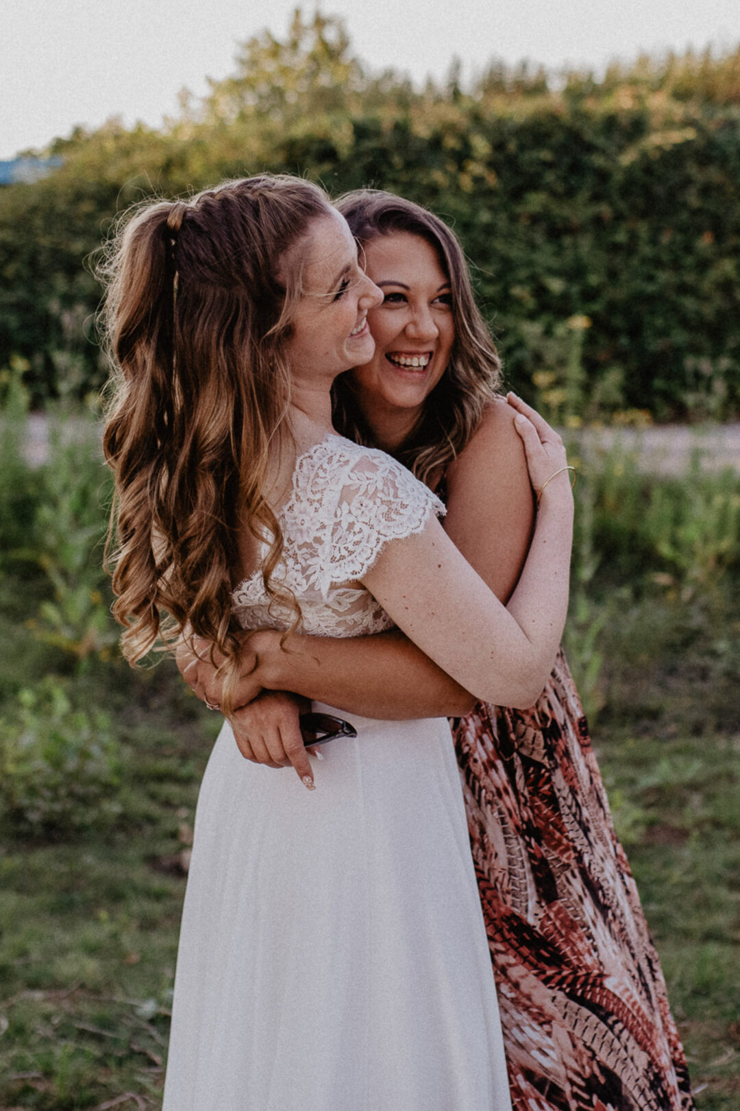 Braut umarmt Freundin lachend