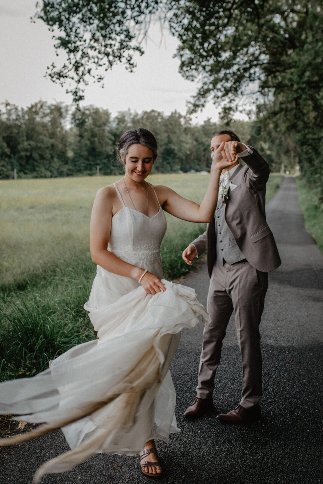 Braut und Bräutigam tanzen ausgelassen im Grünen