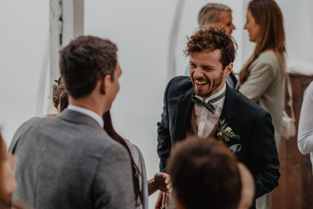 Bräutigam lacht gemeinsam mit Hochzeitsgästen