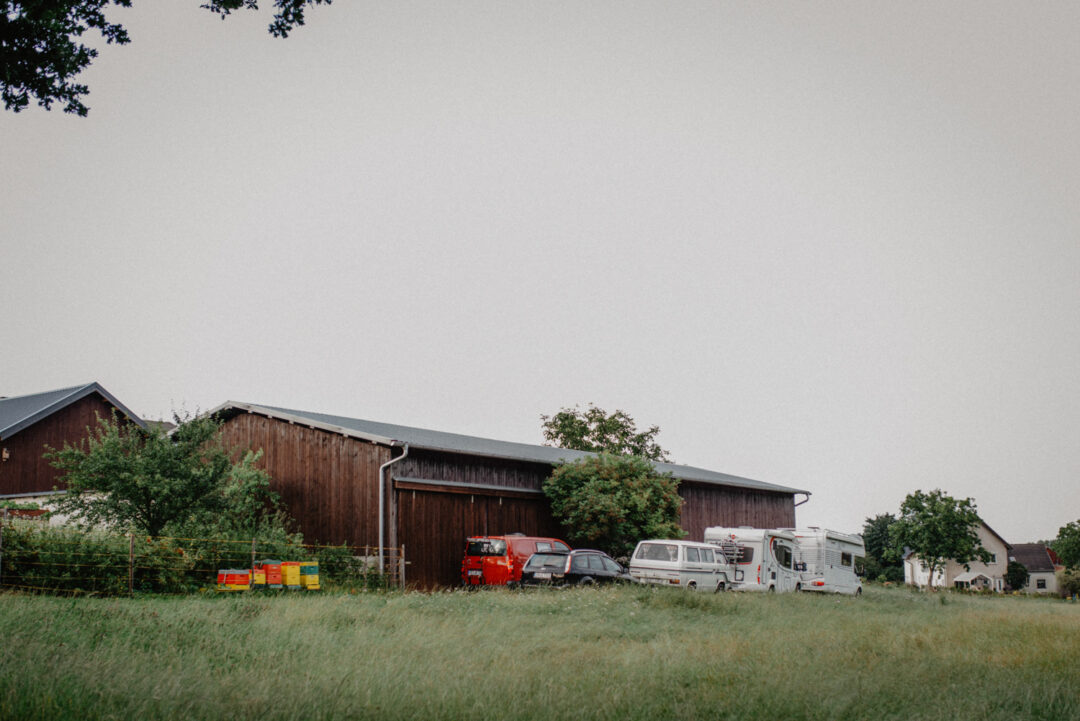 Scheunenhof mit Autos und Wiese im Vordergrund