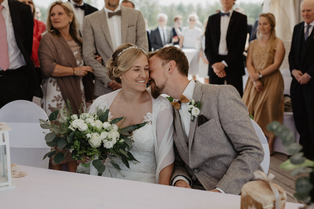 Braut und Bräutigam sitzen nebeneinander und lachen