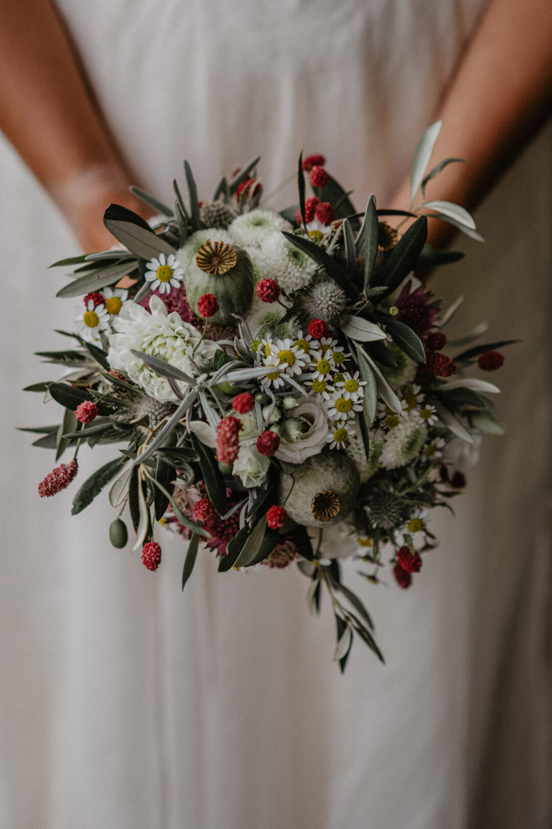 Braut hält natürlichen Wildblumenstrauß mit Mohn