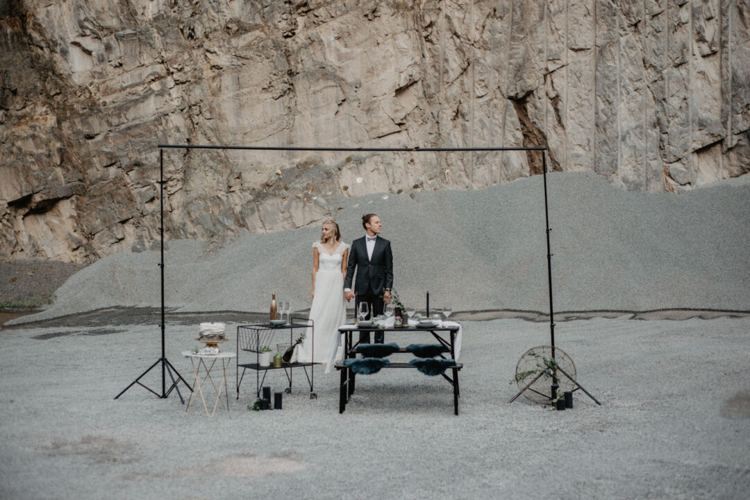 Brautpaar steht an gedecktem Tisch vor Felswand
