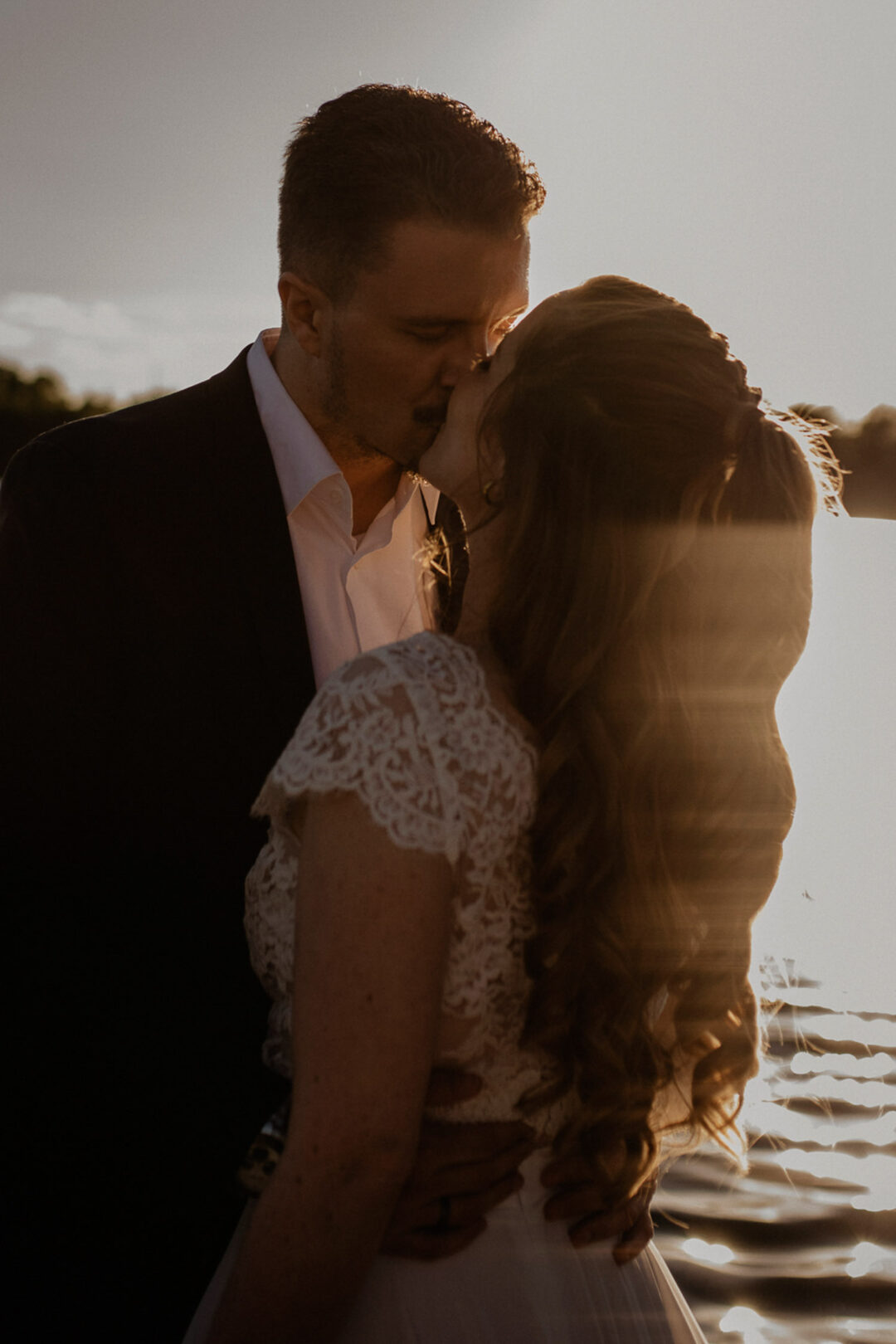Brautpaar küsst sich bei Sonnenuntergang am Sandhofsee