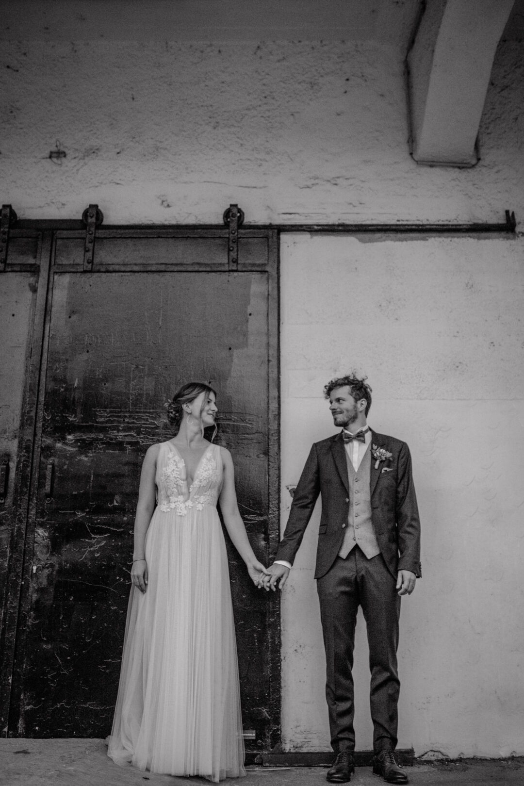 Braut und Bräutigam Hand in Hand vor Industrie-Tor