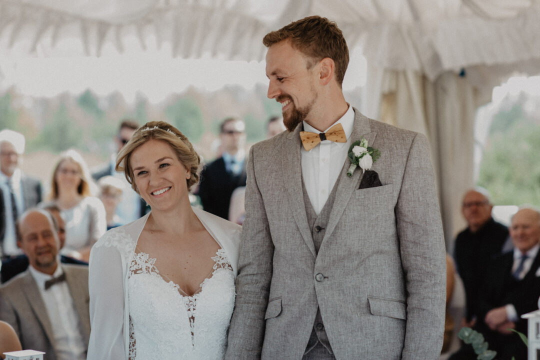 Braut und Braeutigam gehen nebeneinander durch das Zelt