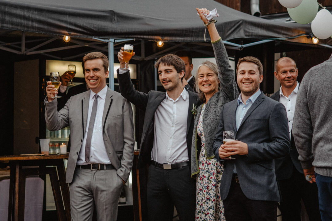 Gäste stoßen an bei Hochzeitsfeier draußen